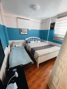 two beds in a room with blue and white walls at JMCL RESIDENCES in Tacloban