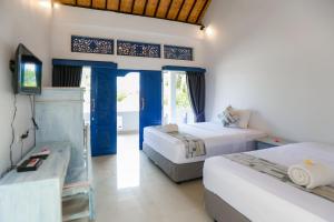 a hotel room with two beds and a desk at Cozy Bungalows in Gili Trawangan