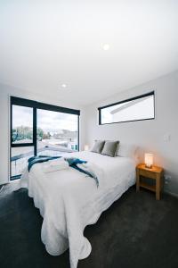 a white bedroom with a large bed and a window at Charming Retreat in the Heart of Christchurch City-CBD 
