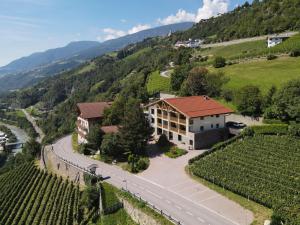 a building on a hill with a road and vineyards at TANOVINUM APARTMENTS Neue moderne Apartments in der Nähe von Klausen Freibad Südtirol Card inklusive in Villandro