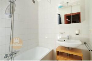 een witte badkamer met een wastafel en een douche bij 4-persoons appartement met een mooi uitzicht in De Panne