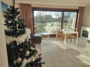 a christmas tree in a living room with a table and chairs at 4-persoons appartement met een mooi uitzicht in De Panne