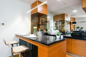 una cocina con encimera negra y armarios de madera en Kl Sentral 2bedroom Muji Family Suite #Netflix 8pax, en Kuala Lumpur