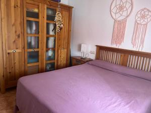 Schlafzimmer mit einem lila Bett und einem Holzschrank in der Unterkunft Las Gaviotas in San Juan de los Terreros