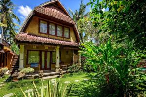 ein kleines Haus inmitten eines Gartens in der Unterkunft Green Sandat 5BR Balinese House CYN in Ubud