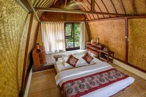 ein Schlafzimmer mit einem großen Bett und einem Fenster in der Unterkunft Green Sandat 5BR Balinese House CYN in Ubud