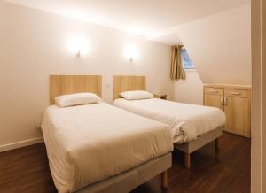 - 2 lits dans une petite chambre dotée de parquet dans l'établissement Garden & City Cauterets Balneo, à Cauterets