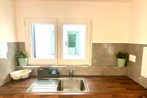 a kitchen with a sink and two windows at Maison chaleureuse proche Paris in Châtillon