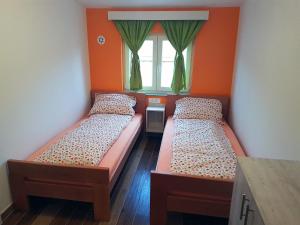 2 camas en una habitación con paredes de color naranja y ventana en Apartment Dora, en Gornji Karin