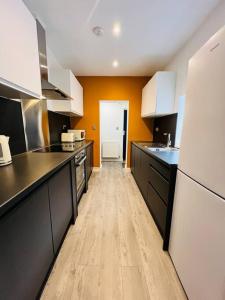 uma grande cozinha com electrodomésticos a preto e branco e pisos em madeira em 4 Beds 3 Bath (2-ensuites) Free Parking 75Mbps em Stoke on Trent