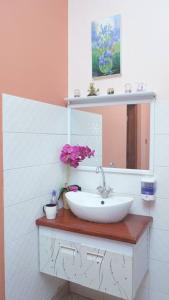 ein Badezimmer mit einem Waschbecken, einem Spiegel und Blumen in der Unterkunft Shimbo Homes in Kutani