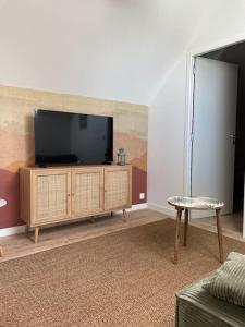 a living room with a flat screen tv on a cabinet at La Martinière in Saint-Martin-sur-Oust
