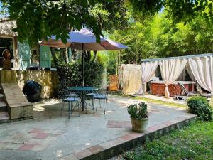 un patio con mesa, sillas y sombrilla en Les Gîtes et la Chambre de Labahou SPA, en Anduze
