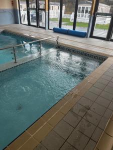 a swimming pool with blue water in a building at Ger-Y-Bwlch - Spacious static on 5star site with Swimming Pool in Benllech
