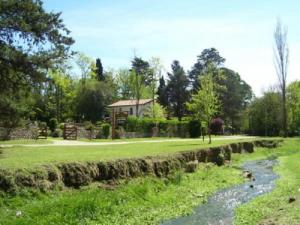 a grassy field with a house in the background and a river at Aldea Kleinwald in Villa General Belgrano