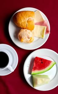 dos platos blancos con comida y una taza de café en HOTEL JP, en Delfinópolis