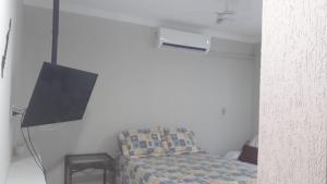 Pokój z łóżkiem, telewizorem i krzesłem w obiekcie Espaço de praia acolhedor para família e pets w mieście Matinhos