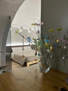 Archome Luxury Apartment في برينديسي: إناء من الزهور على طاولة في غرفة النوم