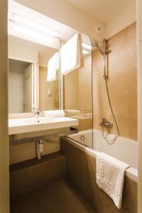 bagno con lavandino, vasca e specchio di Garden & City Cauterets Balneo a Cauterets