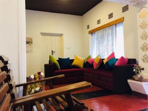 a living room with a couch with colorful pillows at Lodgepole Pine Resorts in Welimada