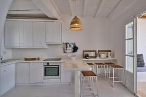une cuisine avec des placards blancs et une lampe pendant dans l'établissement Villa Sea Angels, à Kalafatis