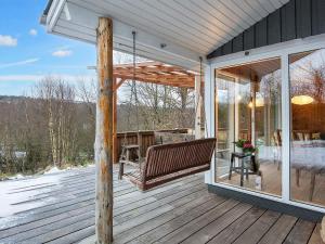 eine Veranda mit einer Bank auf einer Holzterrasse in der Unterkunft Holiday Home Hesselhus in Abildskov