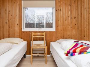 two beds in a room with a window and a chair at Holiday Home Hesselhus in Abildskov