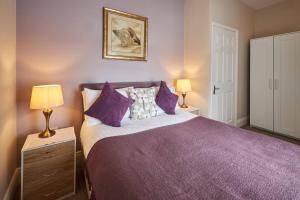 a bedroom with a purple bed with two lamps at Pass the Keys Modern home in a seaside town in Seaham