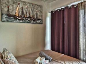 a bedroom with a bed and a painting of boats at C&C Cool View Tagaytay Staycation in Tagaytay +47 photos