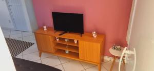 a television sitting on top of a wooden cabinet at Apartamento Vila Aconchego Vermelho in Salvador