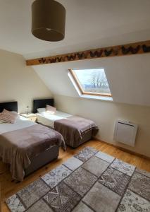 1 dormitorio en el ático con 2 camas y ventana en Vue Du Vallon, en Bersac-sur-Rivalier