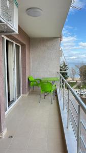 a balcony with two green chairs and a table at Eden’s Apartament in Pogradec +4 photos