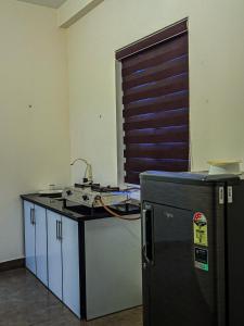 a kitchen with a sink and a refrigerator in a room at Raaha Residency in Kozhikode
