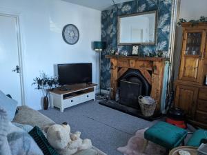 a living room with a teddy bear in front of a fireplace at Cosy cottage with sea & mountain views Carnlough in Carnlough