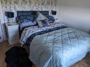 a bedroom with a bed with blue comforter and pillows at Cosy cottage with sea & mountain views Carnlough in Carnlough