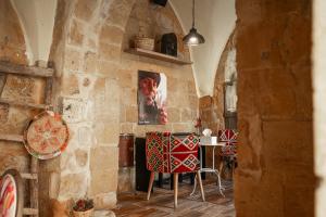 a room with a stone wall with a table and chairs at Jordan Heritage Madhafa in Al Salt