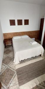 a bedroom with a white bed in a room at Suítes da Praça Tiradentes in Tiradentes