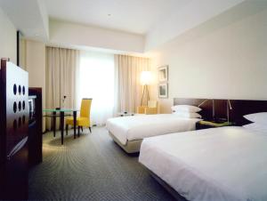 a hotel room with two beds and a desk at Hotel Molino Shin Yuri in Kawasaki