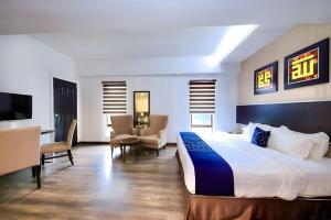 クアラルンプールにあるRPC Blissful Homes & Hotelのベッド、椅子、テレビが備わるホテルルームです。