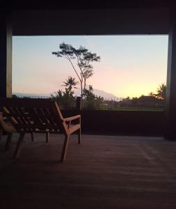 a bench sitting in front of a window with the sunset at Baku living villa in Ngaglik