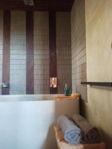 a bathroom with a tub with towels on a shelf at Baku living villa in Ngaglik