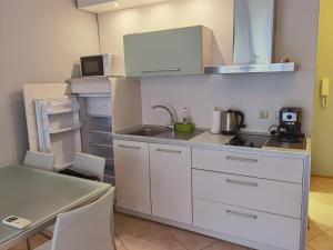 a kitchen with white cabinets and a sink and a table at DL Apartments in Aheloy