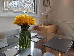 eine Vase gelber Blumen auf einem Glastisch in der Unterkunft Chalet 176 Glan Gwna Park Caernarfon in Caeathro