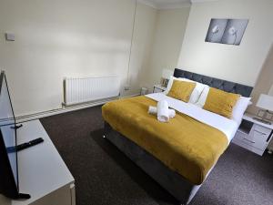 een slaapkamer met een groot bed met een gele deken bij Nariken Apartments, Cardiff in Cardiff