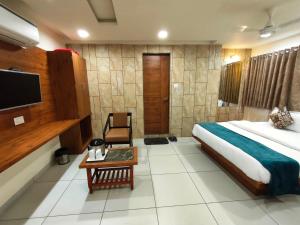 a hotel room with a bed and a tv at Hotel Kinara in Ahmedabad