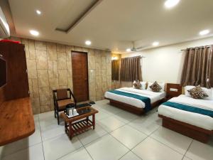 a hotel room with two beds and a table at Hotel Kinara in Ahmedabad