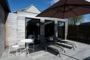 patio con tavolo, sedie e ombrellone di The Suite Escape Suite Wood a Sint-Lievens-Houtem