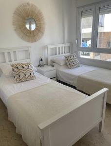 2 camas blancas en una habitación con espejo en Casa Villamartin Plaza Apartment, en Villacosta