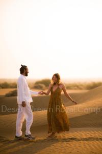 Un uomo e una donna che camminano nel deserto di Desert Dream Royal Camp with Pool a Jaisalmer