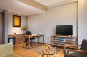 a living room with a flat screen tv and a table at BATIQA Hotel Cirebon in Cirebon